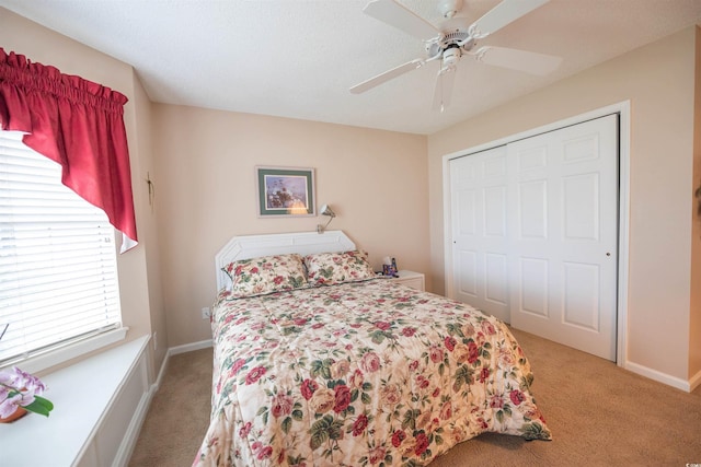 bedroom featuring light colored carpet, a closet, ceiling fan, and baseboards
