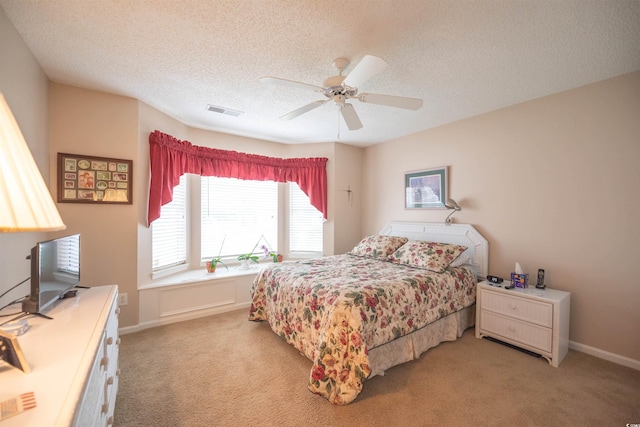 bedroom with light carpet, a textured ceiling, ceiling fan, and baseboards
