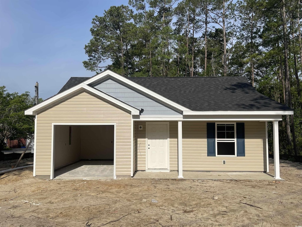 ranch-style home with a shingled roof, an attached garage, covered porch, and driveway