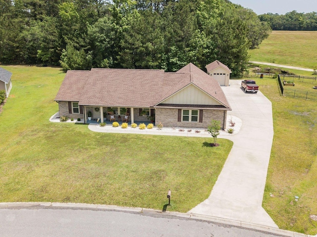 view of front of house with driveway, a porch, brick siding, an outdoor structure, and board and batten siding