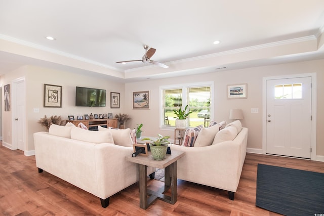 living area featuring ornamental molding, a tray ceiling, plenty of natural light, a ceiling fan, and wood finished floors