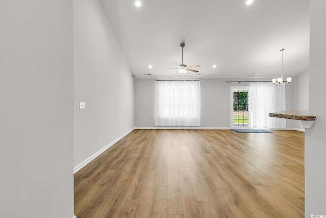 unfurnished living room with light wood-type flooring, recessed lighting, ceiling fan, a chandelier, and baseboards