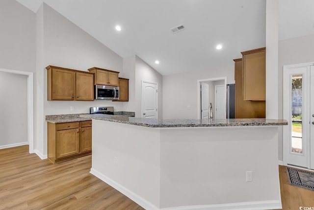 kitchen with stainless steel appliances, light wood finished floors, light stone counters, brown cabinetry, and baseboards