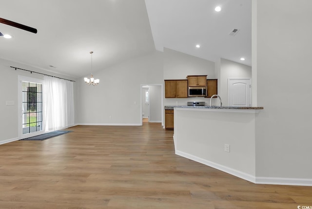 kitchen featuring appliances with stainless steel finishes, a chandelier, brown cabinetry, a ceiling fan, and baseboards