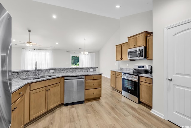 kitchen with stainless steel appliances, a sink, lofted ceiling, light wood-style flooring, and brown cabinetry