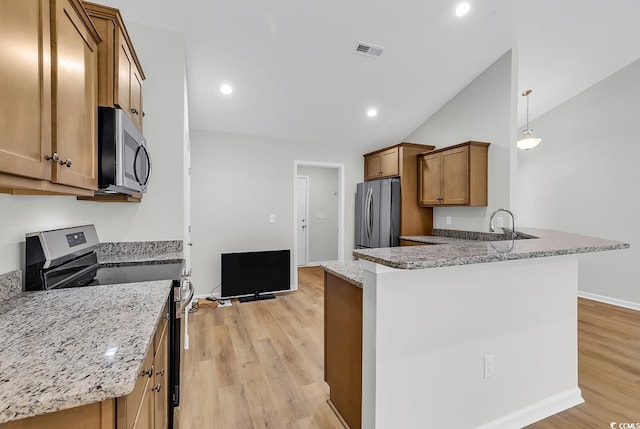 kitchen with appliances with stainless steel finishes, light wood-style floors, brown cabinetry, a peninsula, and light stone counters