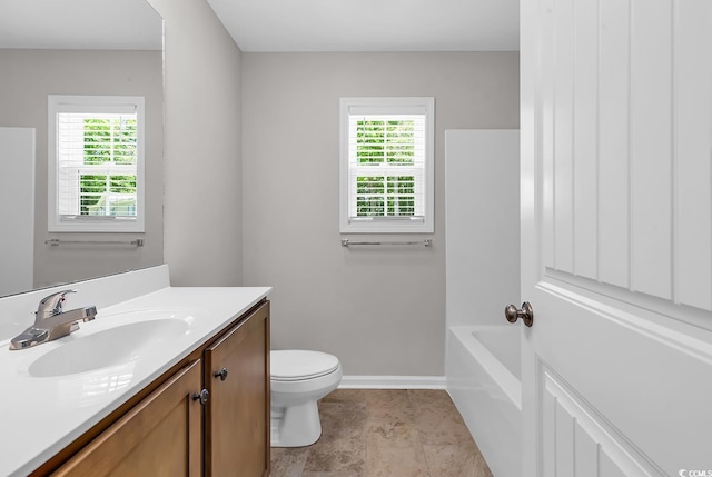 bathroom with plenty of natural light, vanity, toilet, and baseboards
