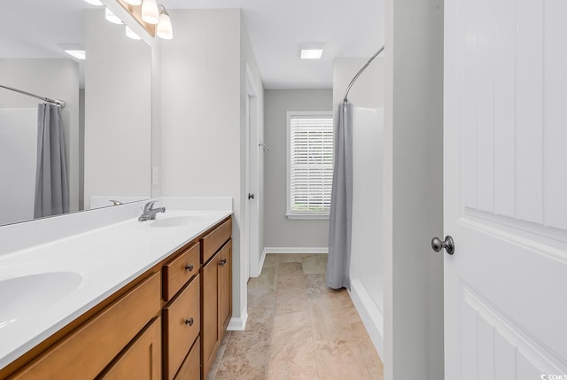 bathroom with curtained shower, double vanity, and baseboards