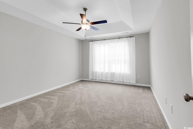 empty room featuring ceiling fan, carpet floors, baseboards, and a raised ceiling