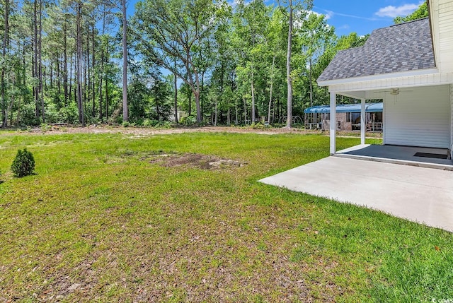 view of grassy yard with ceiling fan and a patio area