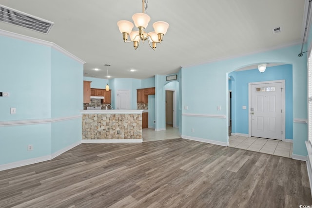 6244 Catalina Dr Unit 511, North Myrtle Beach, SC 29582 - unfurnished living room with arched walkways, a chandelier, light wood-style floors, baseboards, and crown molding