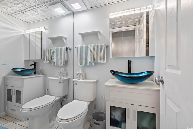 bathroom with toilet, vanity, and tile patterned flooring