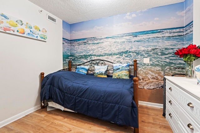 bedroom with light wood-style floors, a textured ceiling, and baseboards