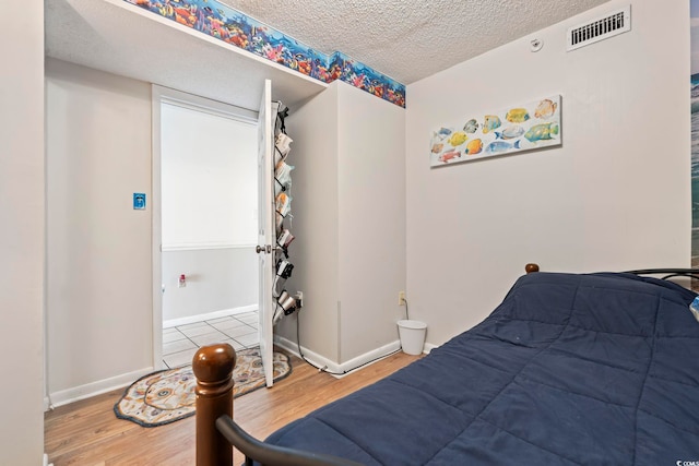 bedroom with wood finished floors, a textured ceiling, and baseboards