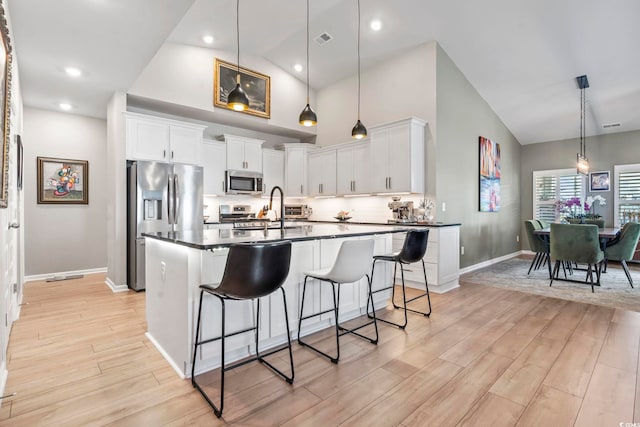 122 New Paradise Way, Myrtle Beach, SC 29588 - kitchen with appliances with stainless steel finishes, dark countertops, light wood-style flooring, a kitchen breakfast bar, and high vaulted ceiling