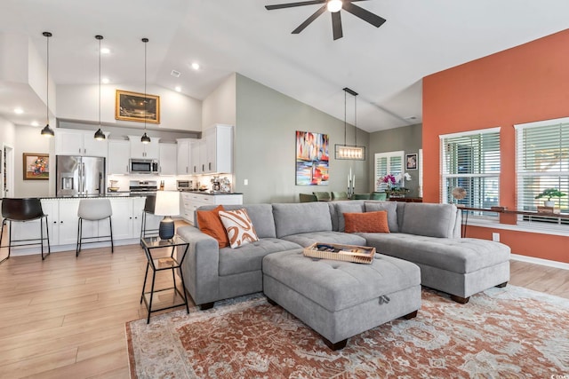 living room with ceiling fan, light wood-type flooring, and high vaulted ceiling