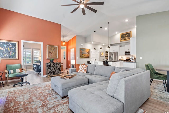 living room with high vaulted ceiling, a ceiling fan, and light wood-style floors