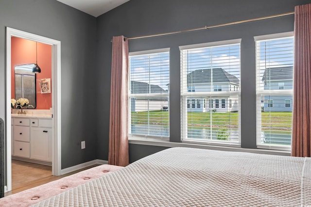 bedroom featuring multiple windows, baseboards, and connected bathroom
