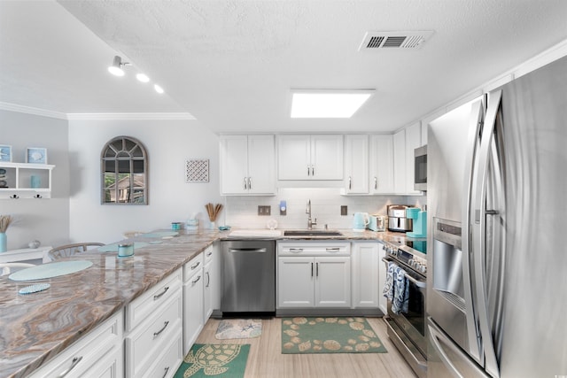 307 74th Ave N Unit 3C, Myrtle Beach, SC 29572 - kitchen with stainless steel appliances, a sink, ornamental molding, white cabinets, and tasteful backsplash
