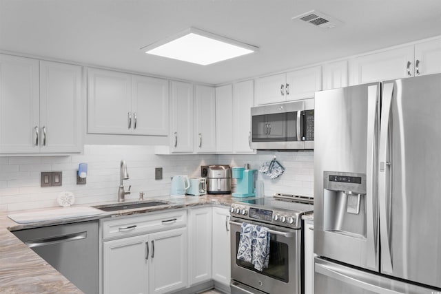 307 74th Ave N Unit 3C, Myrtle Beach, SC 29572 - kitchen featuring appliances with stainless steel finishes, a sink, white cabinets, backsplash, and light stone counters