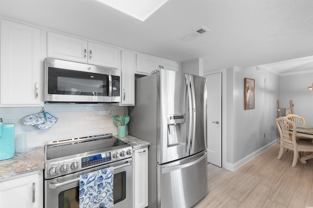 307 74th Ave N Unit 3C, Myrtle Beach, SC 29572 - kitchen with appliances with stainless steel finishes, white cabinetry, decorative backsplash, baseboards, and light wood-style floors