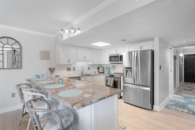 307 74th Ave N Unit 3C, Myrtle Beach, SC 29572 - kitchen featuring appliances with stainless steel finishes, a sink, a peninsula, light stone counters, and white cabinets