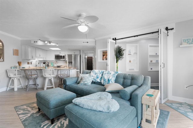 307 74th Ave N Unit 3C, Myrtle Beach, SC 29572 - living room with a barn door, ornamental molding, baseboards, ceiling fan, and light wood finished floors