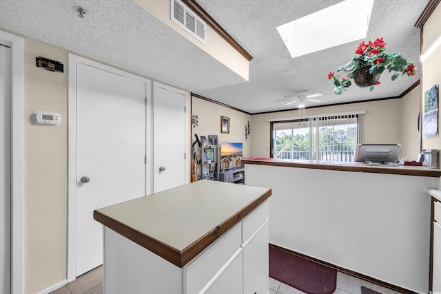 4350 Intercoastal Dr Unit 2402, Little River, SC 29566 - kitchen with a textured ceiling, light tile patterned floors, a skylight, white cabinetry, and a center island
