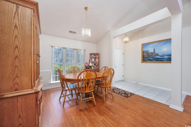 dining space with a chandelier, lofted ceiling, baseboards, and light wood finished floors
