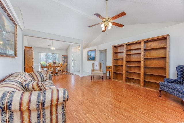 living room with light wood-type flooring, vaulted ceiling, ceiling fan, and baseboards