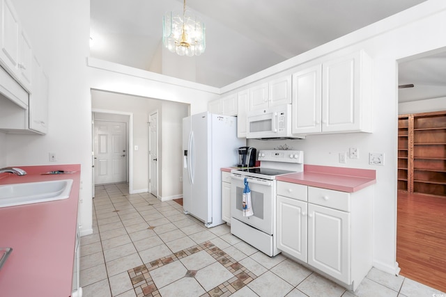 kitchen featuring white appliances, light tile patterned floors, a sink, white cabinets, and a chandelier