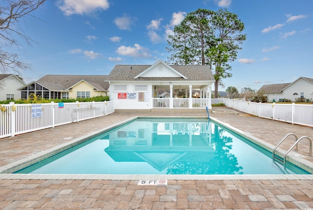 community pool with a patio, fence, and an outbuilding