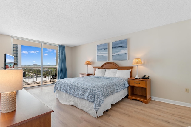 9820 Queensway Blvd Unit 804, Myrtle Beach, SC 29572 - bedroom with expansive windows, access to exterior, light wood-style flooring, a textured ceiling, and baseboards