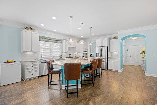 1290 Prescott Cir, Myrtle Beach, SC 29577 - kitchen featuring appliances with stainless steel finishes, a kitchen island, a breakfast bar, white cabinetry, and arched walkways