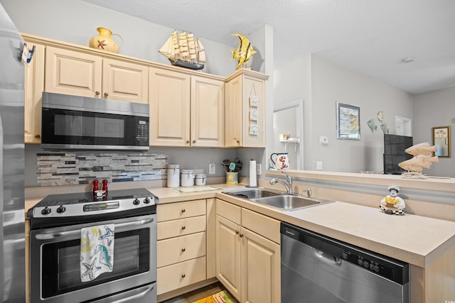 kitchen featuring appliances with stainless steel finishes, a peninsula, a sink, backsplash, and light countertops