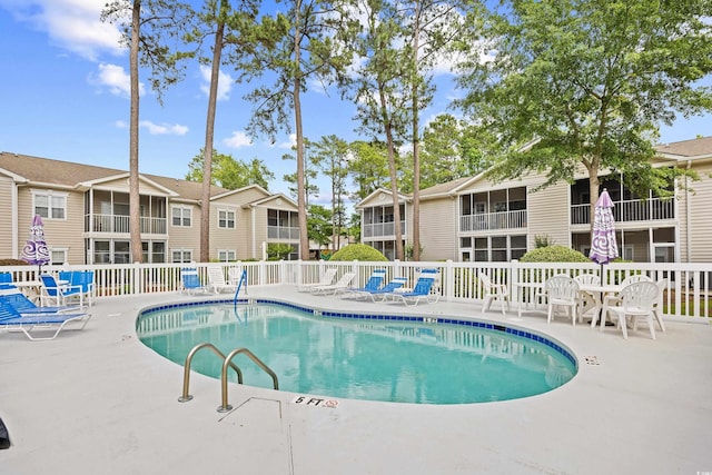 community pool featuring a residential view, a patio area, and fence