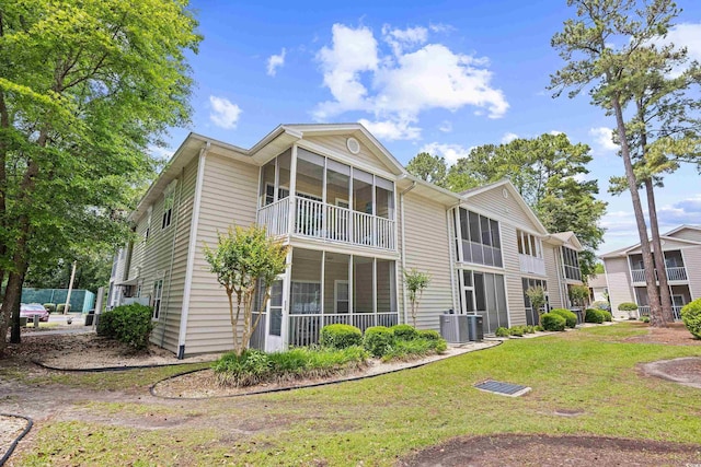 back of property featuring a lawn, a sunroom, and cooling unit
