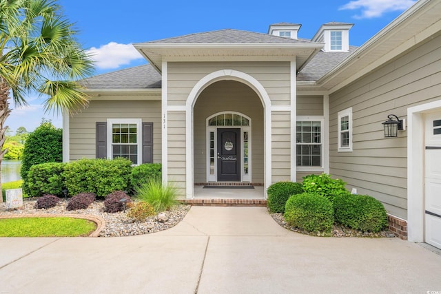 entrance to property featuring roof with shingles