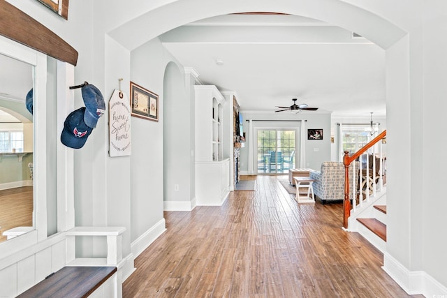 entrance foyer featuring arched walkways, wood finished floors, ceiling fan, and baseboards