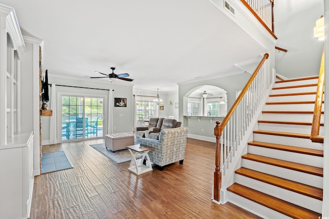 living area featuring ceiling fan, ornamental molding, stairway, baseboards, and wood finished floors