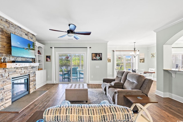 living area with dark wood finished floors, a ceiling fan, a fireplace, baseboards, and a chandelier