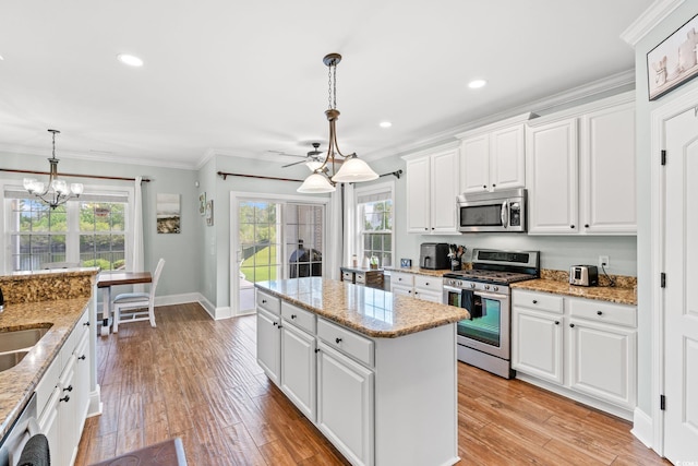 kitchen featuring appliances with stainless steel finishes, a kitchen island, crown molding, white cabinetry, and light wood-type flooring