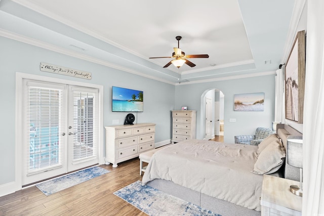 bedroom featuring arched walkways, access to outside, a raised ceiling, wood finished floors, and ornamental molding