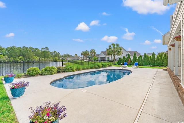 view of swimming pool with a patio area, fence, and a water view
