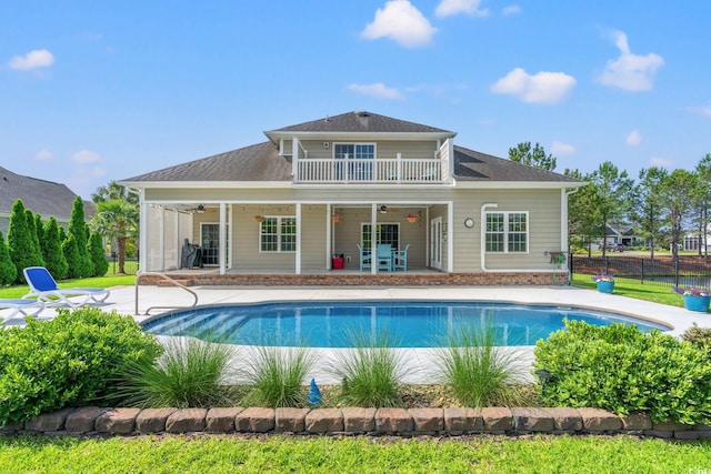 back of house with ceiling fan, a balcony, a patio area, fence, and an outdoor pool