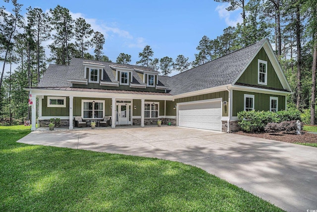 view of front facade with covered porch, a standing seam roof, an attached garage, a front lawn, and a shingled roof