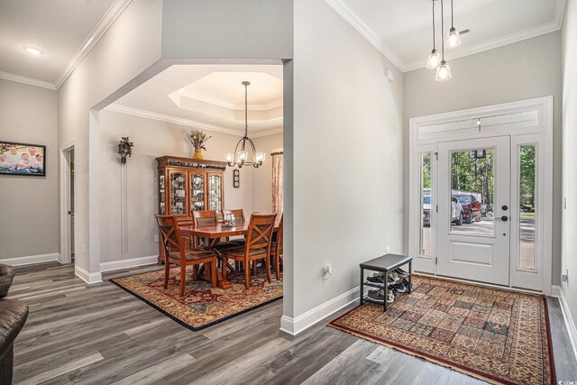 entrance foyer with wood finished floors, ornamental molding, a chandelier, and baseboards