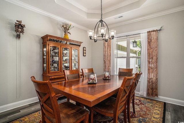 dining space with a chandelier, a tray ceiling, dark wood finished floors, baseboards, and crown molding
