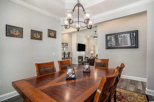dining area with a chandelier, a fireplace, wood finished floors, baseboards, and crown molding