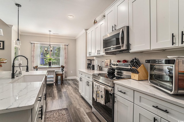 kitchen featuring appliances with stainless steel finishes, a sink, ornamental molding, a chandelier, and dark wood-type flooring